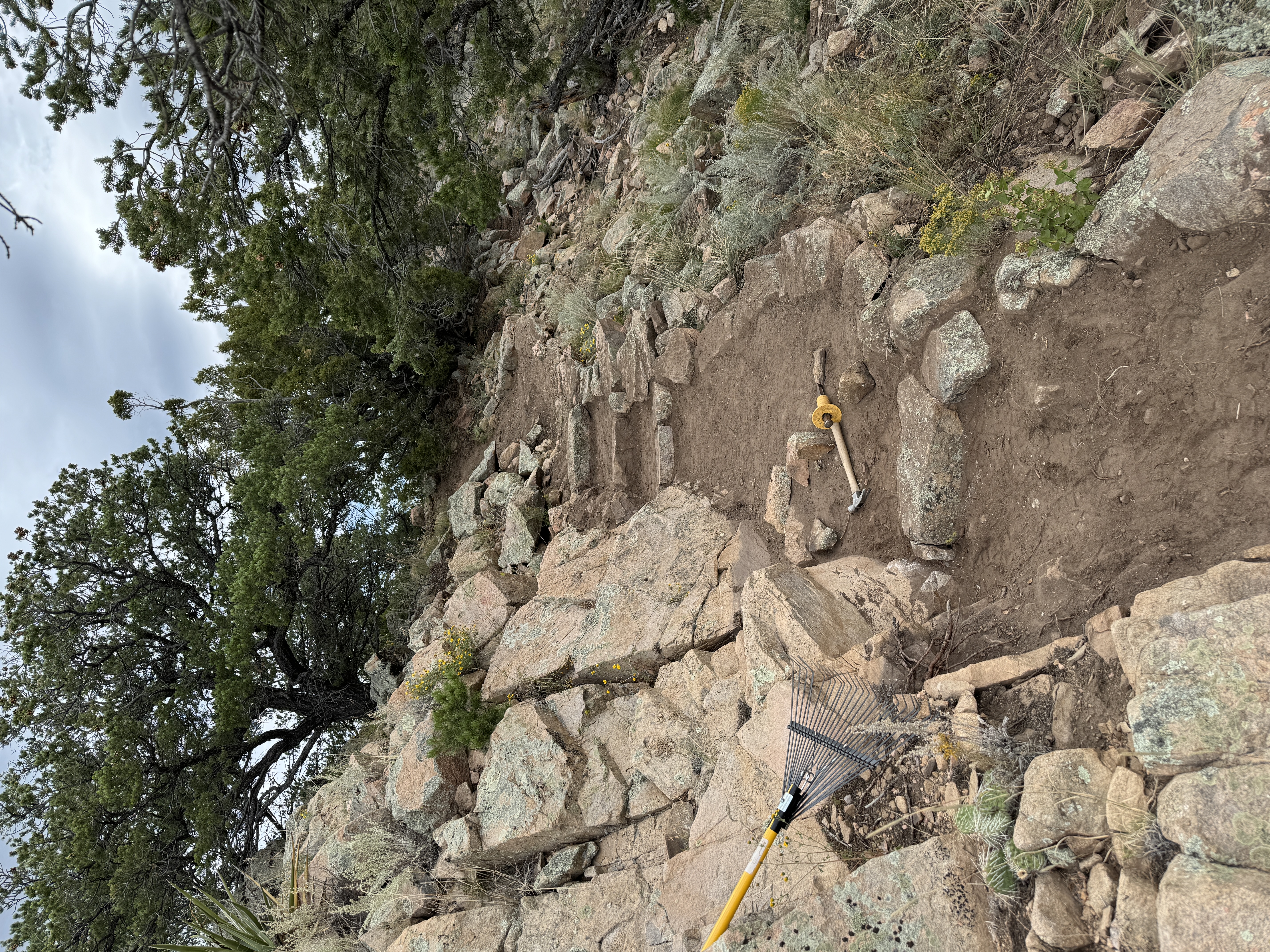 Stone wall detail — rake and tools against dry-stacked wall on ridge